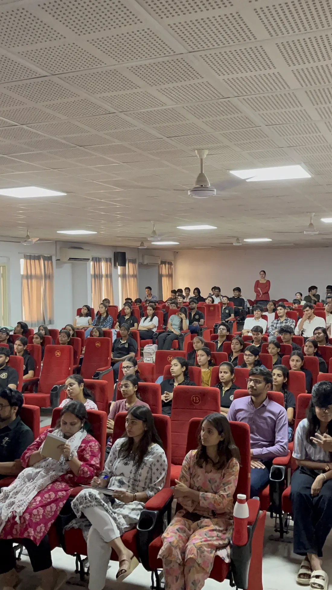 Rows of seated students and guests in a hall during a felicitation ceremony