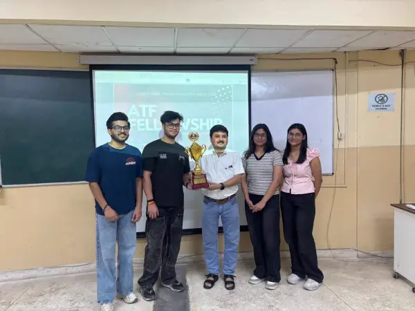 Five students and a faculty member holding a trophy in front of a slide reading ATF Fellowship