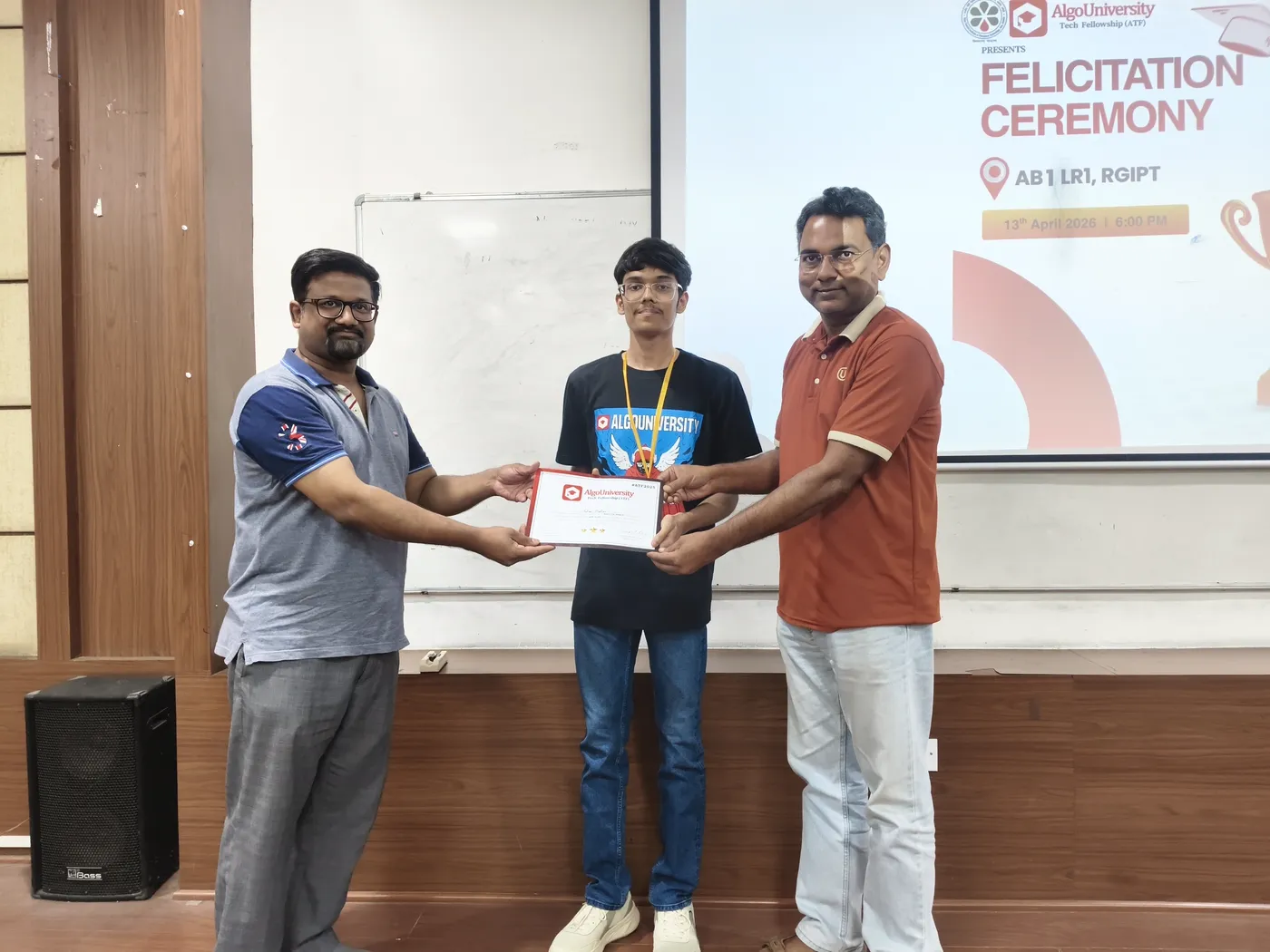 An ATF fellow receiving his certificate from two faculty members at the RGIPT felicitation ceremony, under the ceremony slide