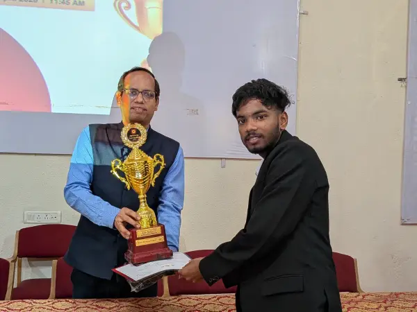 A faculty member presenting a large trophy and a certificate to an ATF fellow at a felicitation ceremony